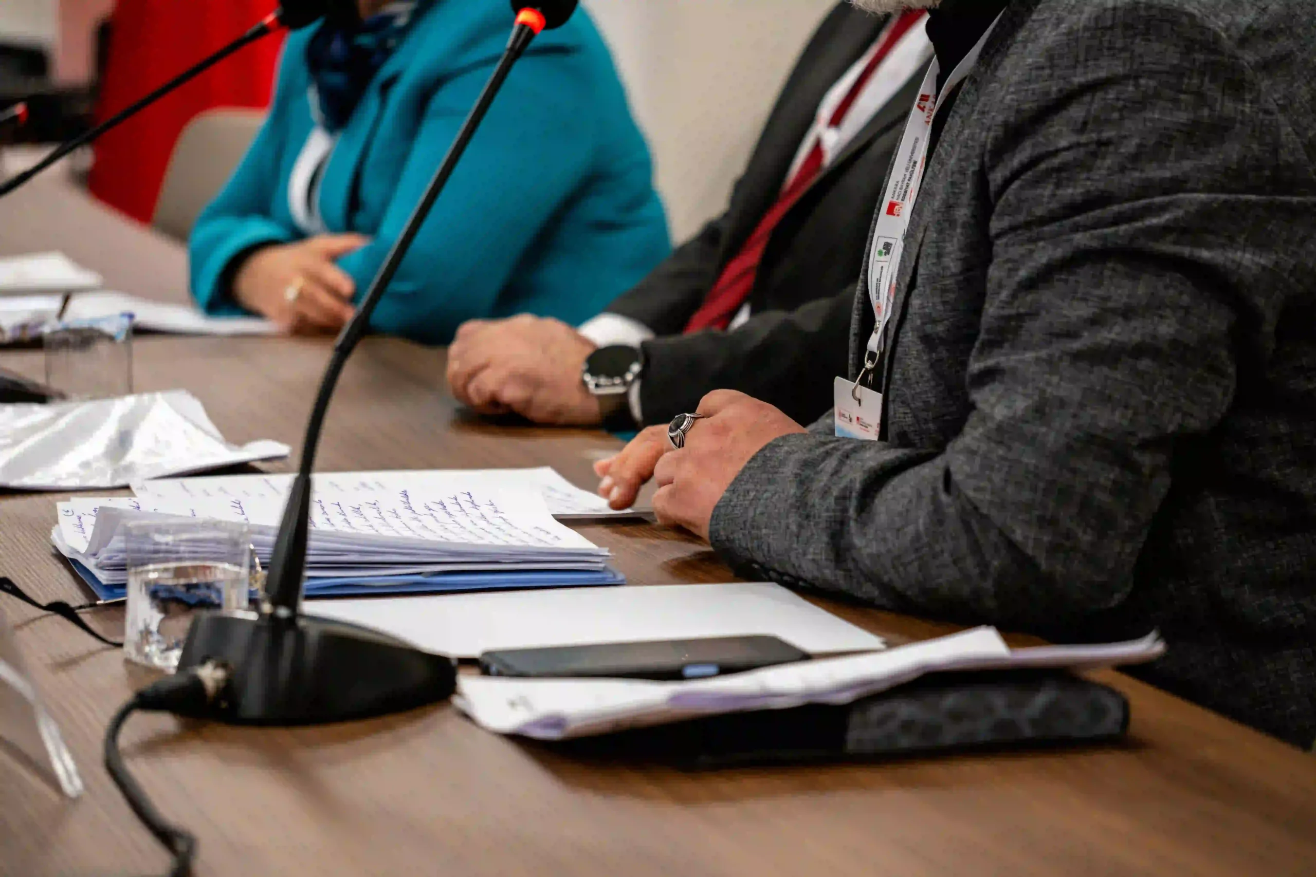 Plusieurs intervenants sont assis derrière des microphones et des documents lors d’une conférence de presse.