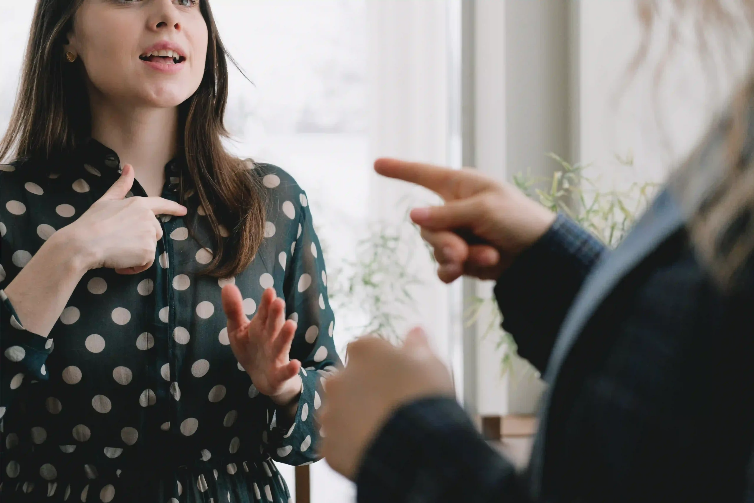 Deux personnes échangent vivement en utilisant des gestes lors d’une discussion professionnelle.