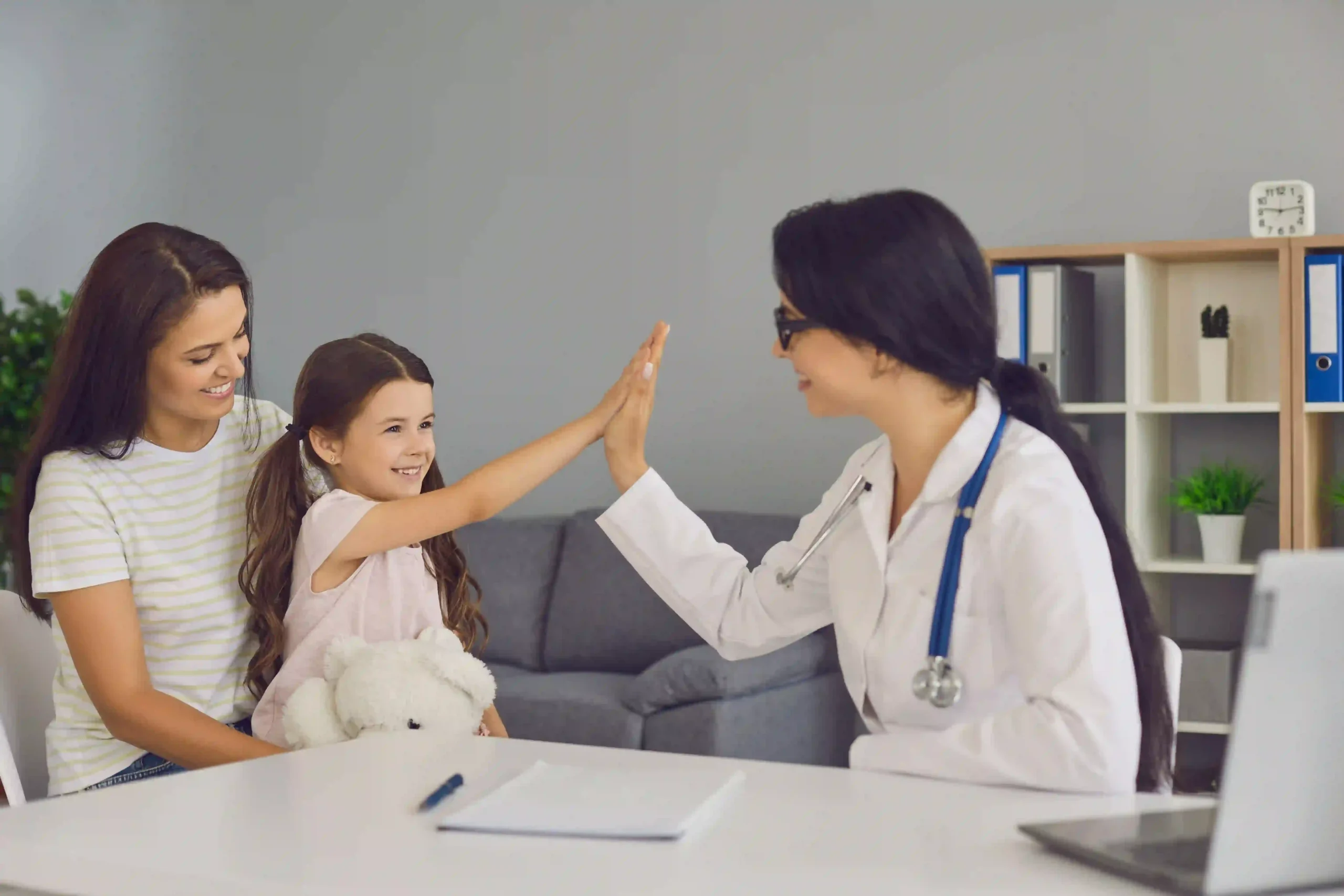 Une pédiatre et une petite fille se tapent dans la main pendant une consultation.