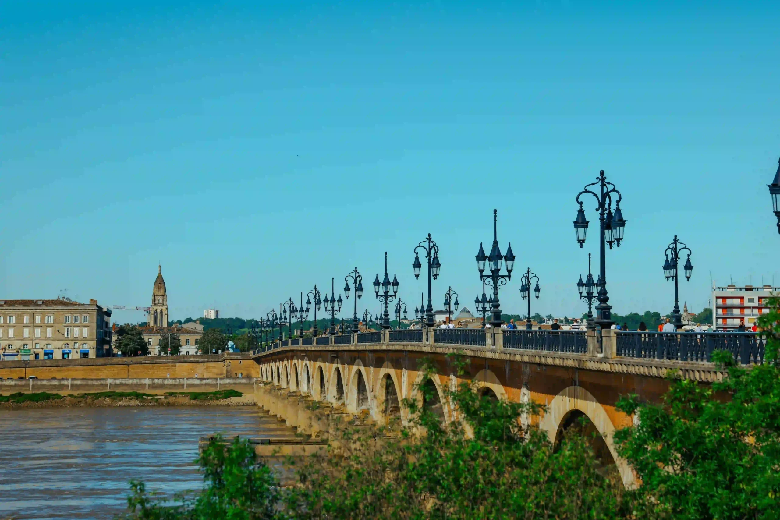 Vue du pont de pierre de Bordeaux sous un ciel bleu.