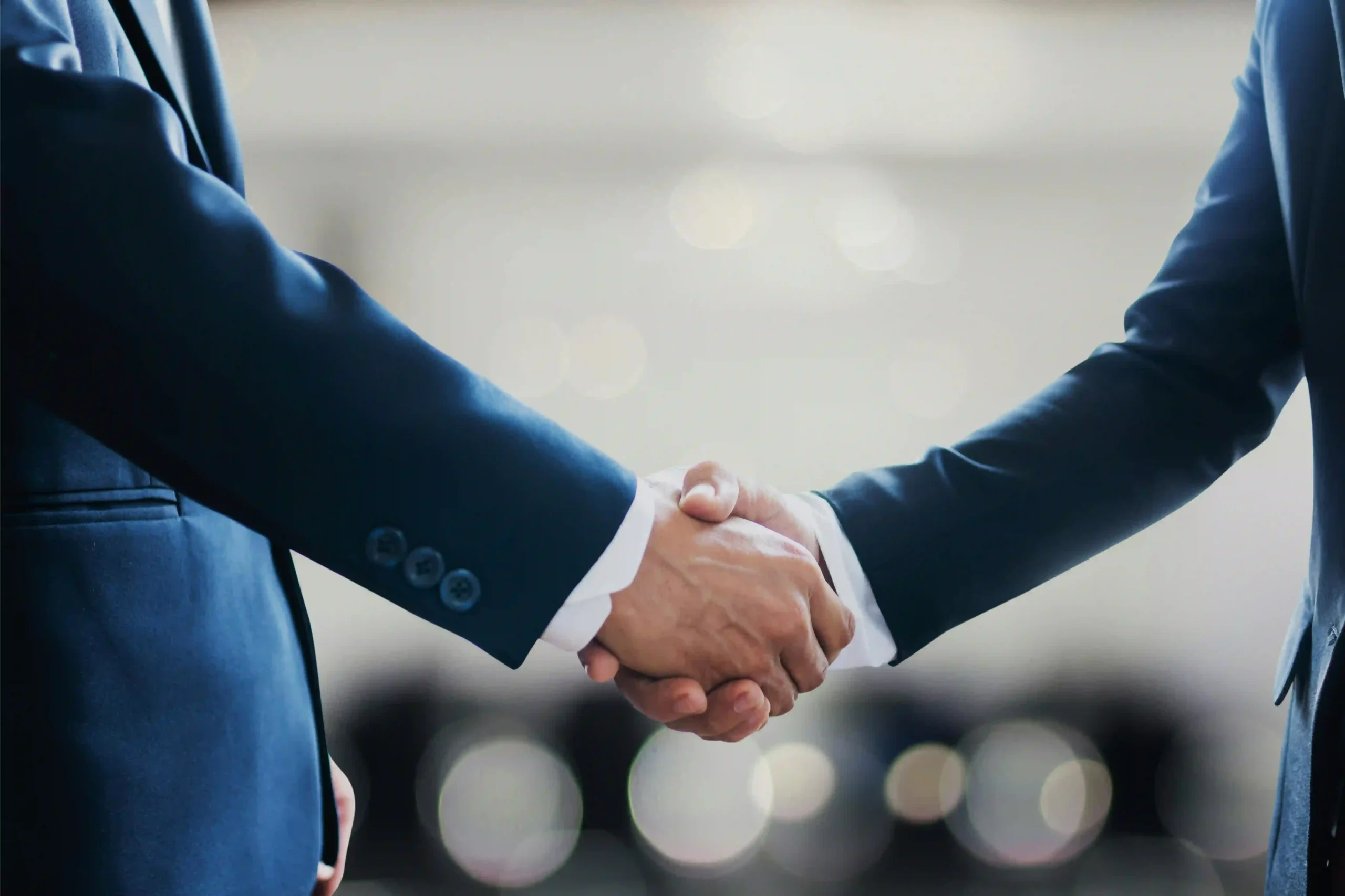 Deux personnes en costume se serrent la main pour conclure un accord professionnel.