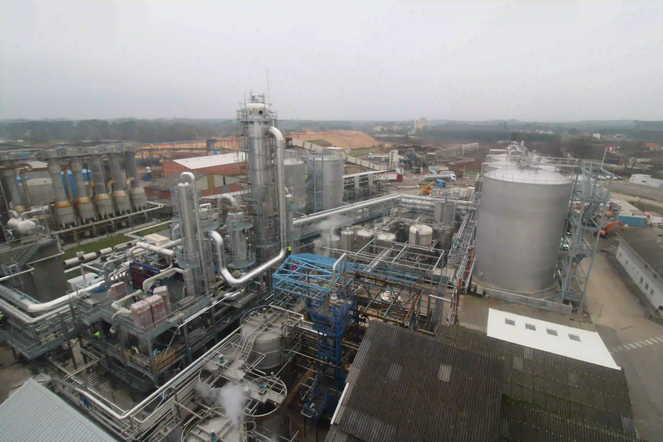 Vue aérienne d’un site industriel composé de cuves, de tours et de réseaux de canalisations.