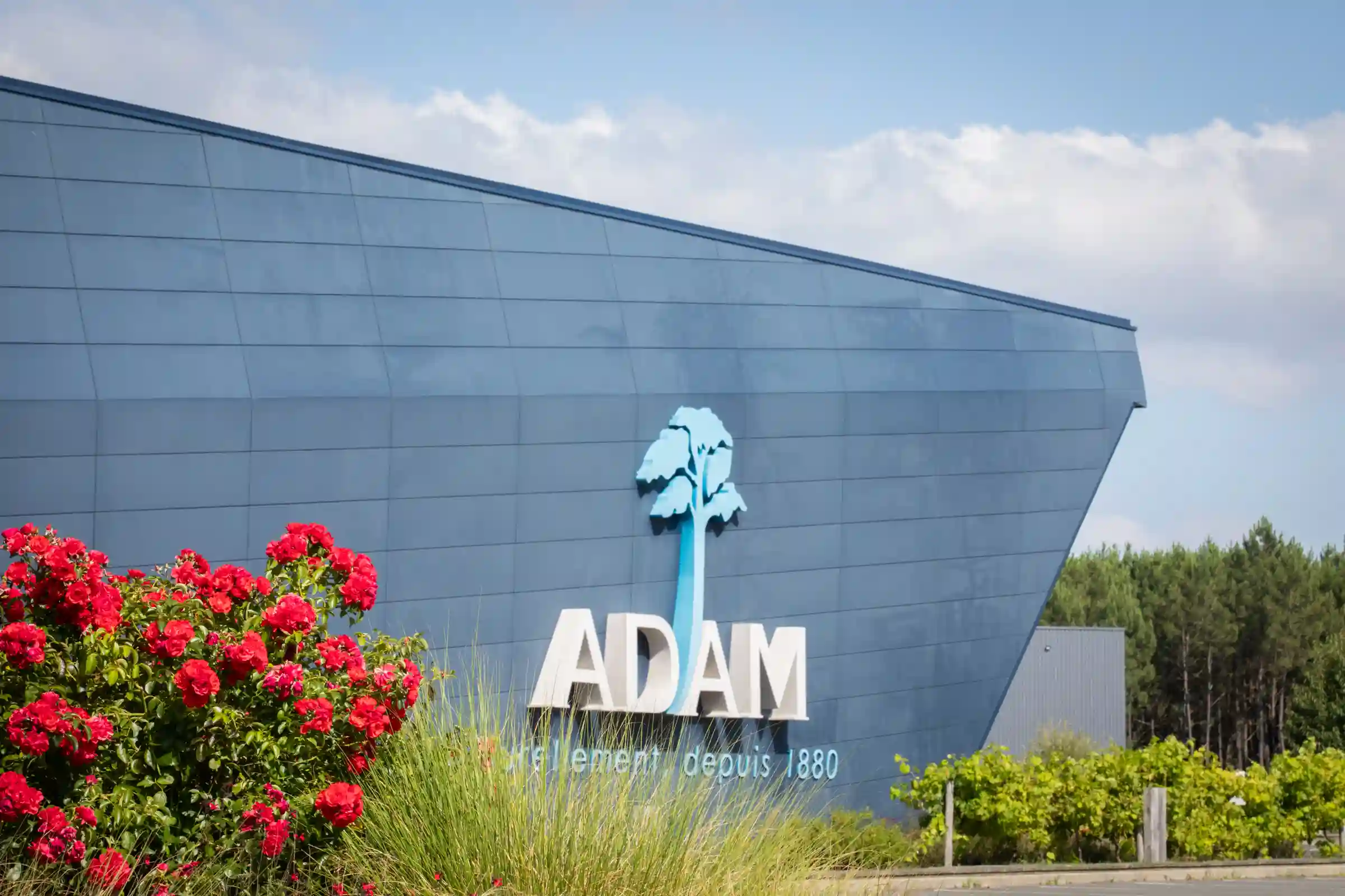 Façade du site de l’entreprise ADAM entourée de végétation