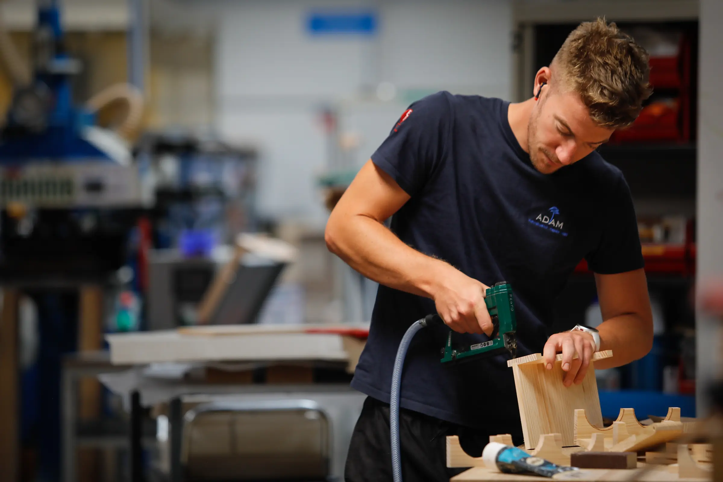 Salarié d’ADAM assemblant une pièce en bois dans un atelier
