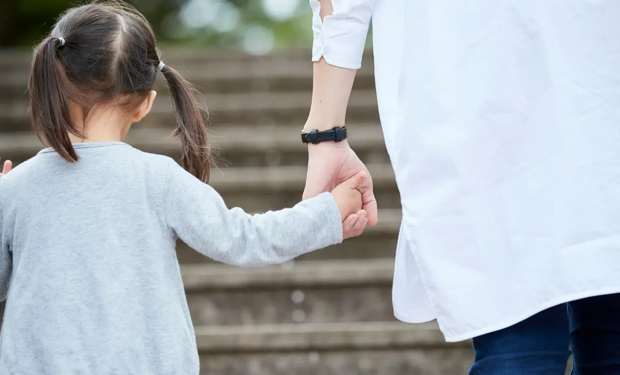 Enfant tenant la main d’un adulte en marchant